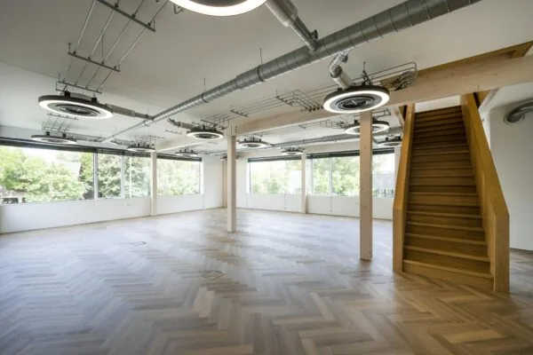 Licht en modern kantoorinterieur aan de Fred. Roeskestraat met visgraatvloer, houten trap en industriële plafonddetails.